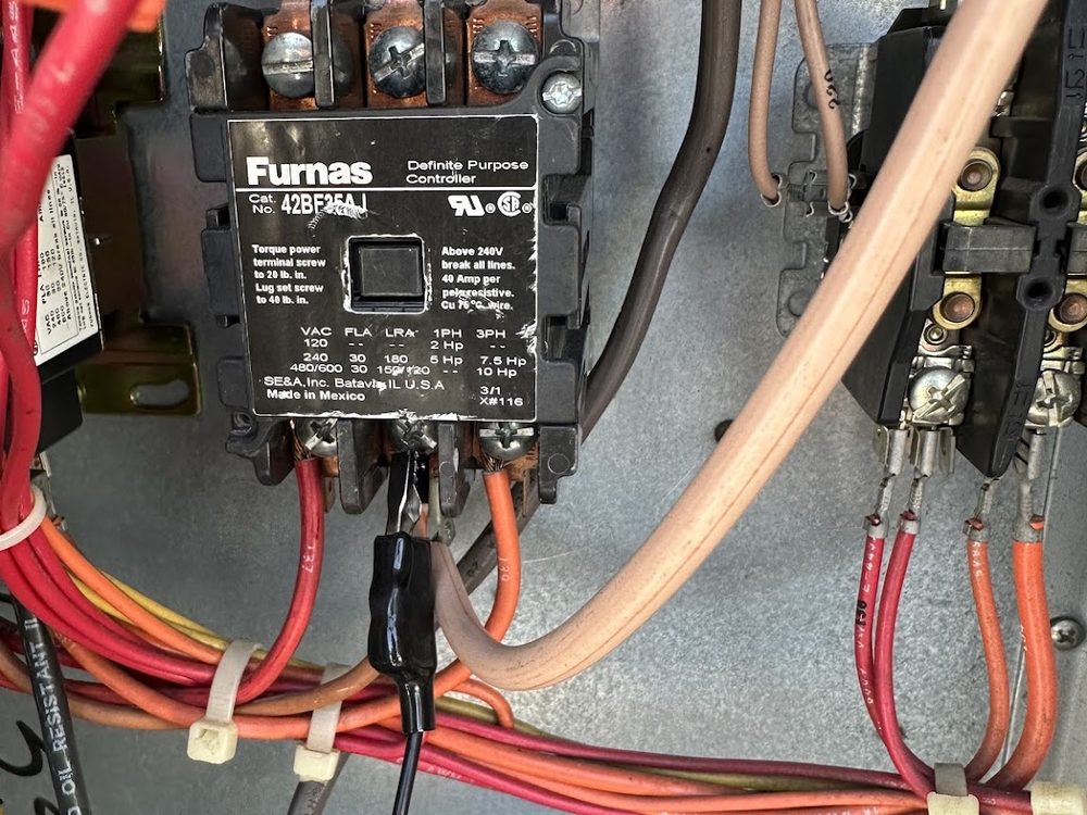 A technician working inside an HVAC electrical control panel